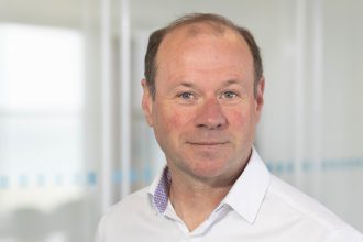 Professional portrait of a man in a white shirt, industry publication context, no vessels shown.
