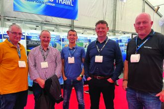 Fishermen at industry exhibition with fishing vessels and gear in background in Denmark.