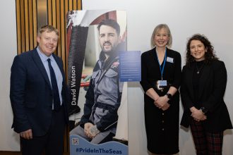 Fishermen and industry representatives at a commercial fishing event with a promotional poster in a.