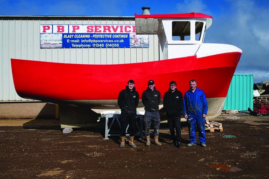 Red fishing vessel at shipyard with crew in front, commercial fishing industry context.