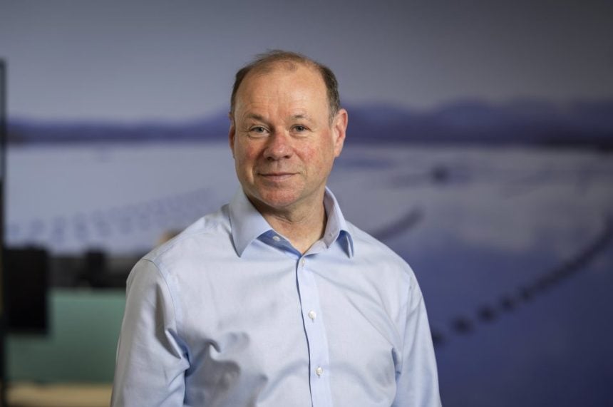 Portrait of a man in a white shirt with a blurred maritime background.