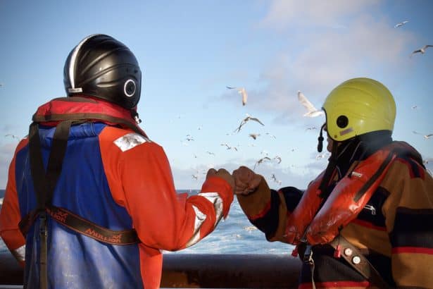 fishermen bumping fists in the deck of a trawler