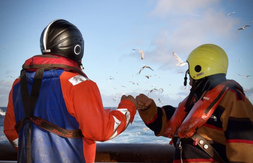 fishermen bumping fists in the deck of a trawler