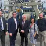 Group of five people standing in front of a fishing boat at Castletownbere harbor.