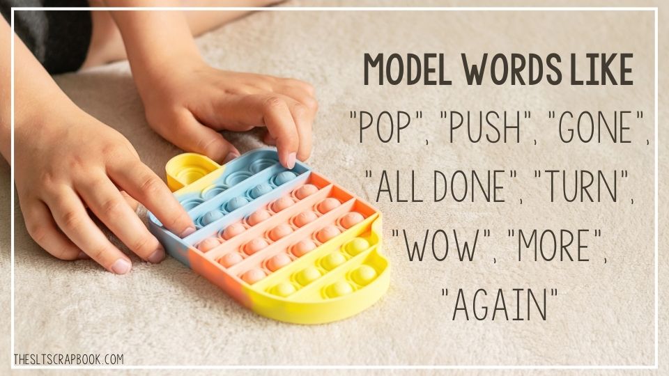 Picture of a child's hands popping an ice cream style popper toy. The text on the right reads "model words like pop, push, gone, all done, turn, wow, more, again".