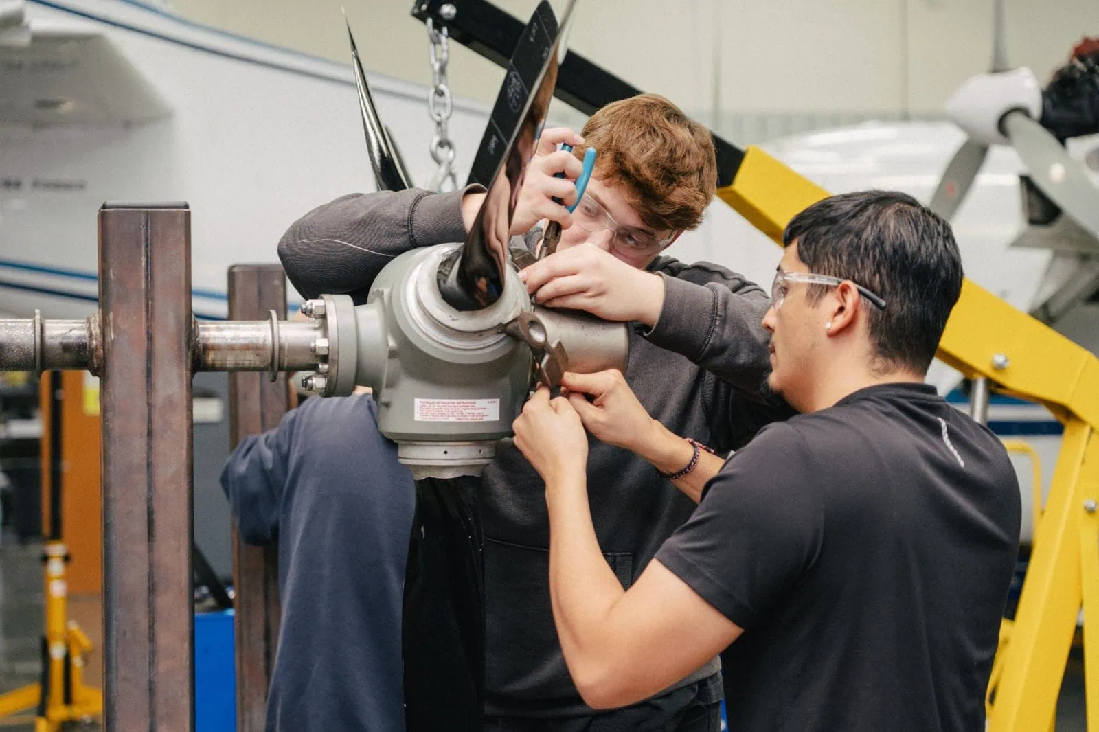aviation maintenance students working with their hands on airplane