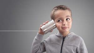 A young boy holding a tin can phone, demonstrating a fun and creative way to communicate.