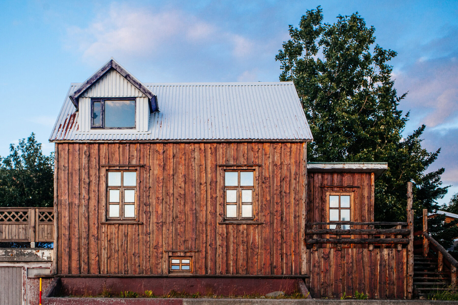 Rustic wooden house with a metal roof under a cloudy sky.