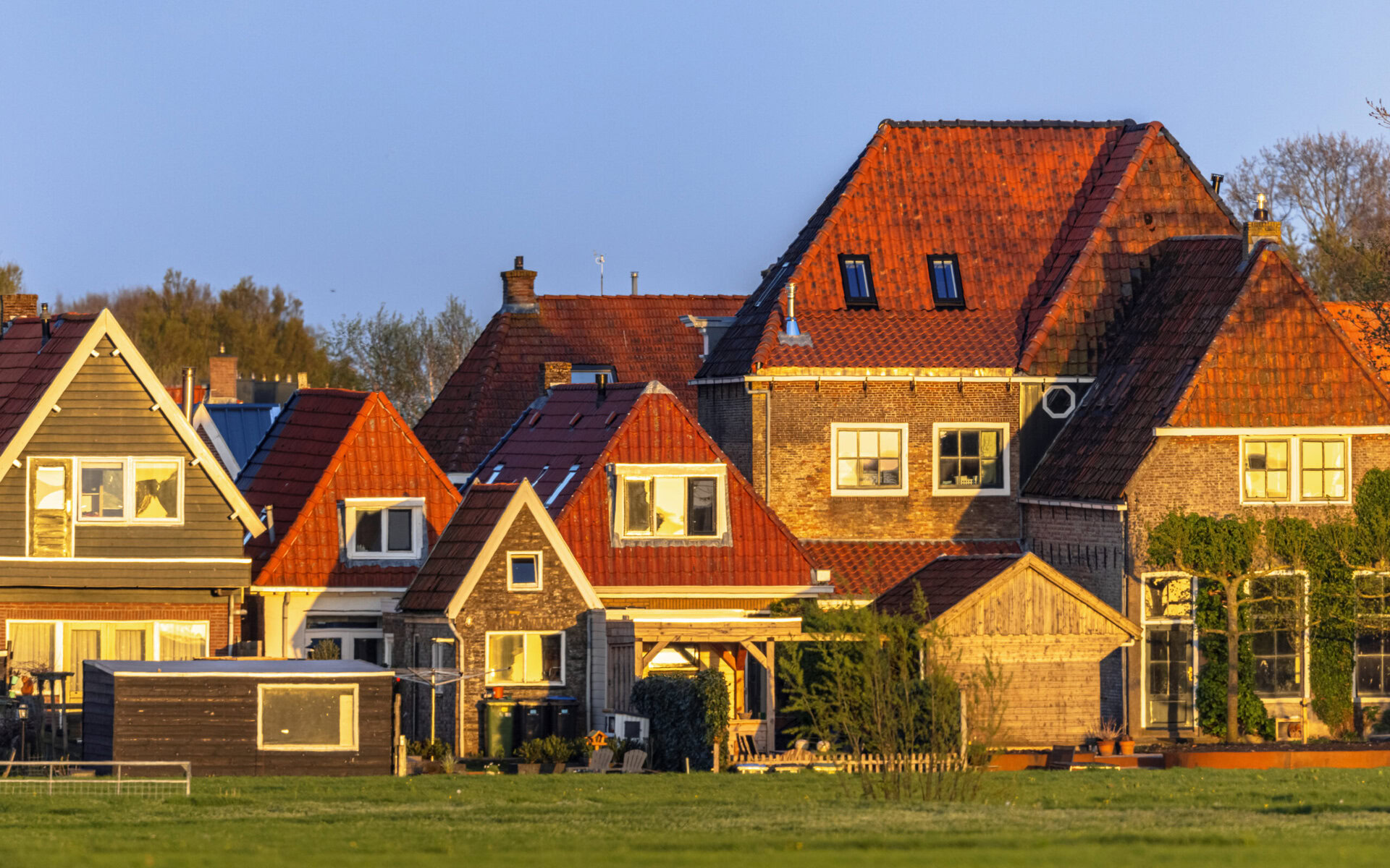 Row of houses with red tile roofs and brick facades at sunset