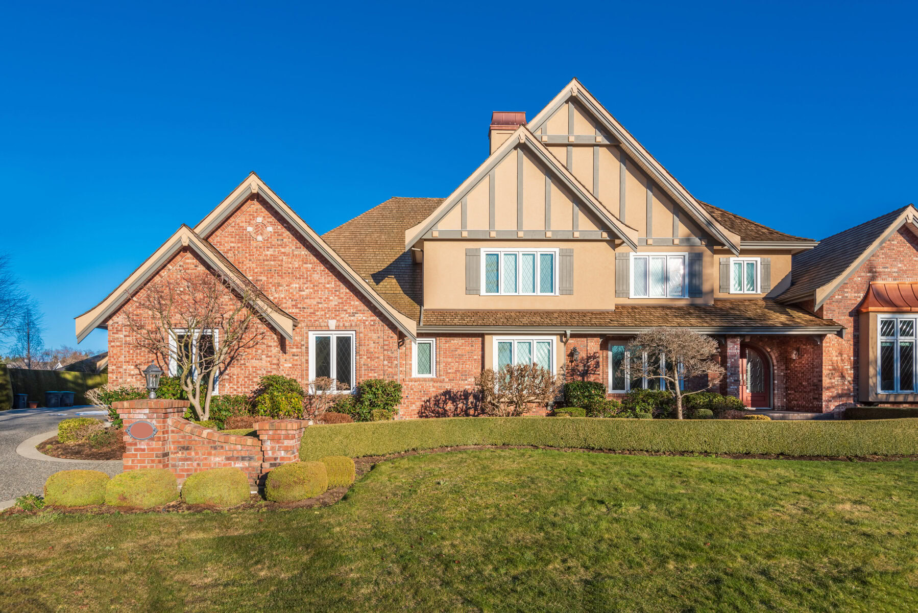 Large brick and stucco house with multiple gables and a green lawn.