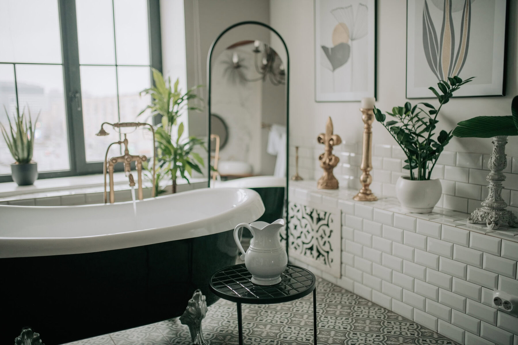 A stylish bathroom with a black and white clawfoot tub and plants.
