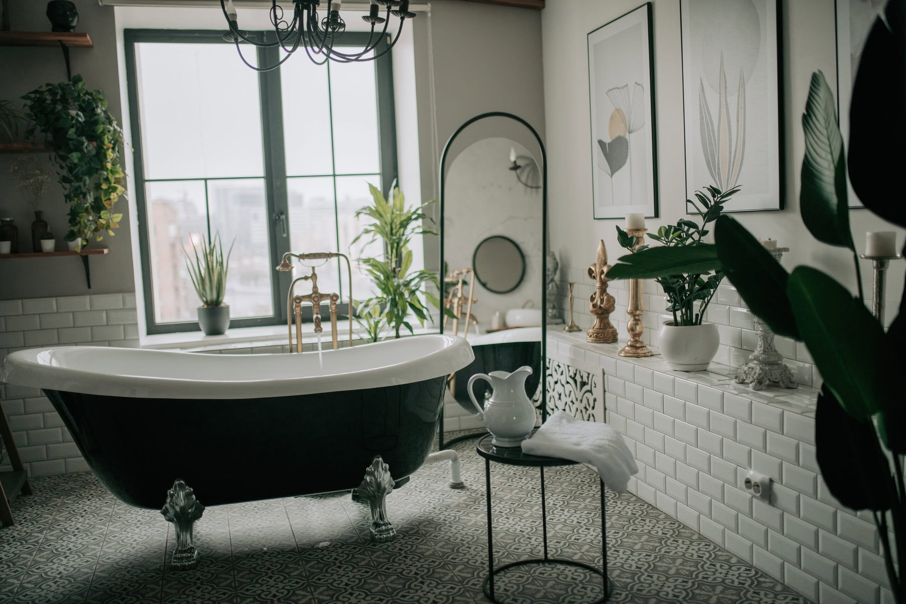 A black and white clawfoot bathtub in a bright, plant-filled bathroom.