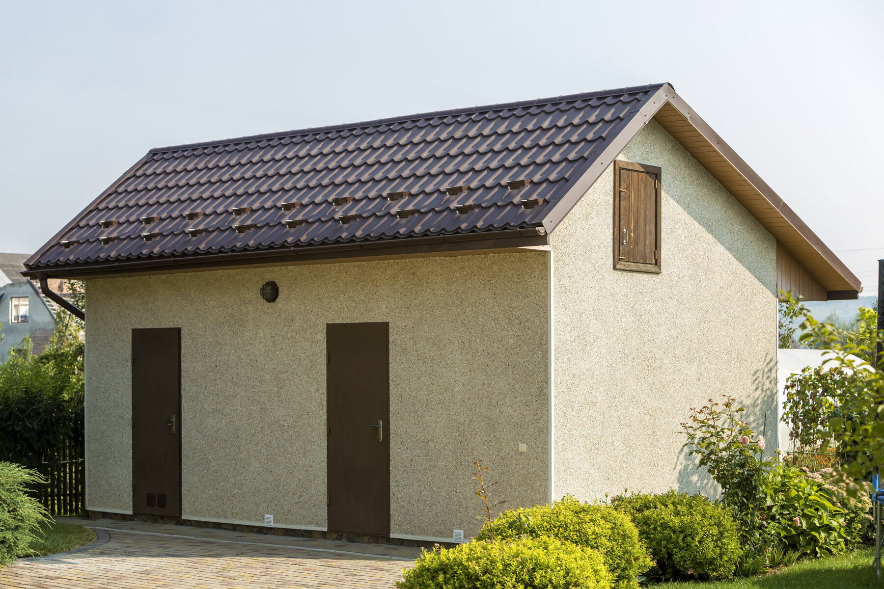 Small beige outbuilding with brown roof and two brown doors