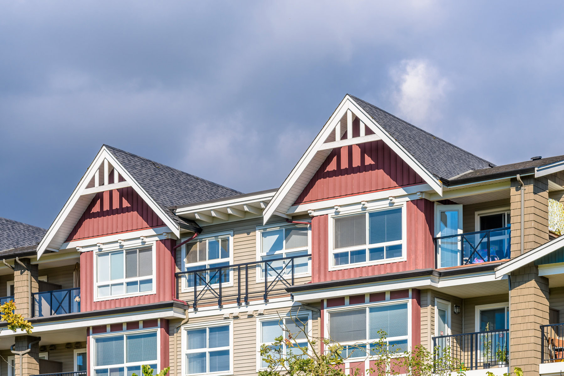 Top floors of a modern apartment building with red and beige siding.