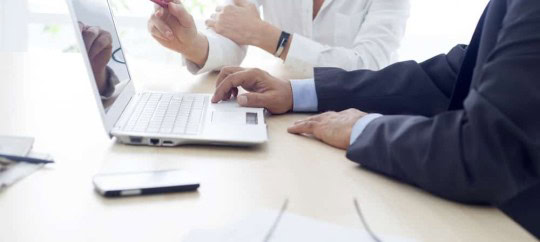 Business professionals discussing on laptop at Trust Point.