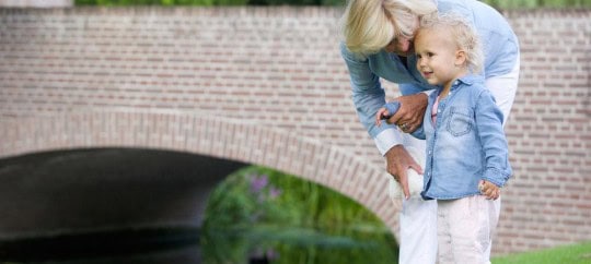 Grandmother and young girl enjoying time outdoors near a brick bridge.