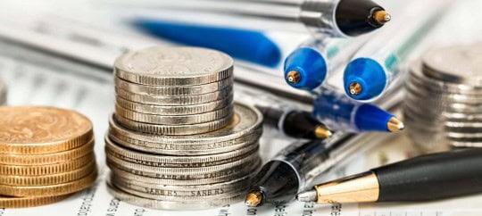 Stacks of coins with pens and documents for financial analysis.