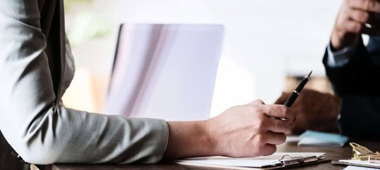 Business professionals discussing at a meeting table with documents and a laptop.