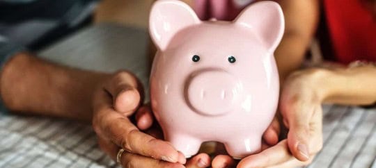 Pink piggy bank held by hands, symbolizing savings and financial security.