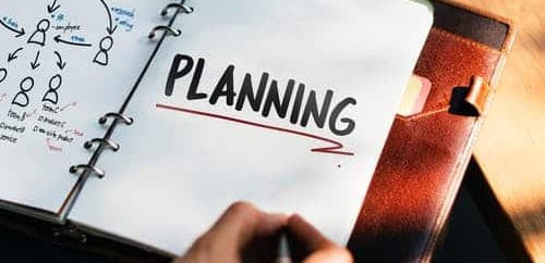 Open planner with 'PLANNING' written on page, business strategy notes visible.
