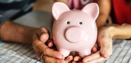 Pink piggy bank held by hands, symbolizing savings and financial security.