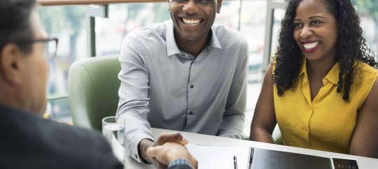 couple shaking hands with business man after deal; financial advisor