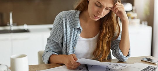Woman analyzing financial documents in a modern kitchen setting.