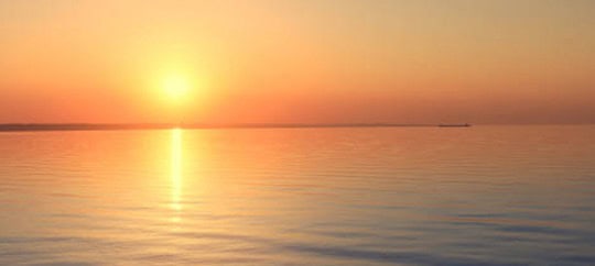 Beautiful sunset over tranquil water at Trust Point, emphasizing serenity and natural beauty.