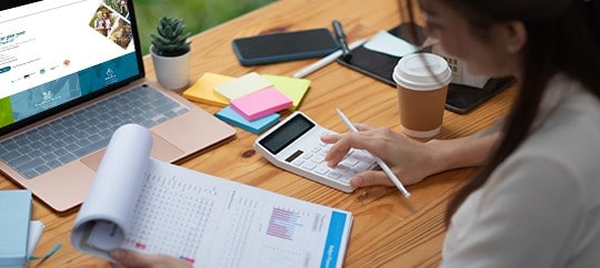 Businesswoman working at desk with laptop, documents, and coffee.