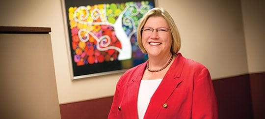 Smiling woman in red blazer at Trust Point office.