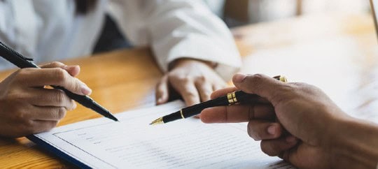 People reviewing document with pens pointing at things