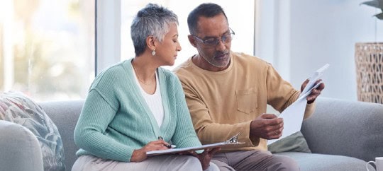 couple looking at documents sitting on couch