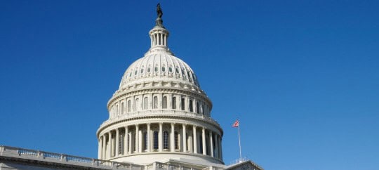 Capitol dome with American flag, symbol of government and trust.