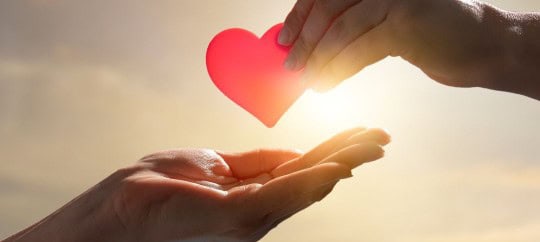 A person handing another person a paper heart