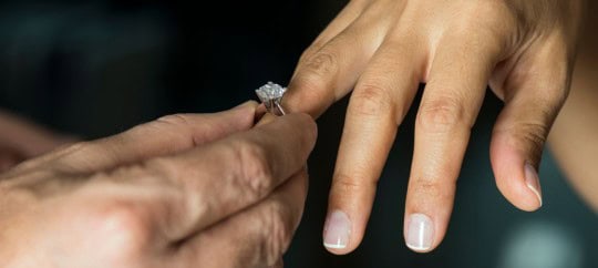 Man putting a wedding ring on a womans finger