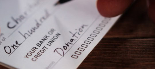 Person writing on a check to donate to charity