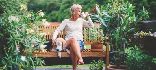 Woman sitting on a bench with coffee and a dog