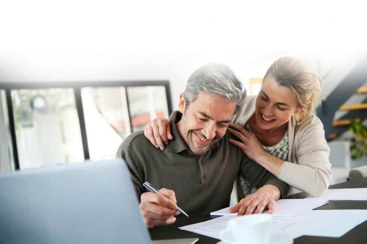 Couple smiling over a paper and laptop