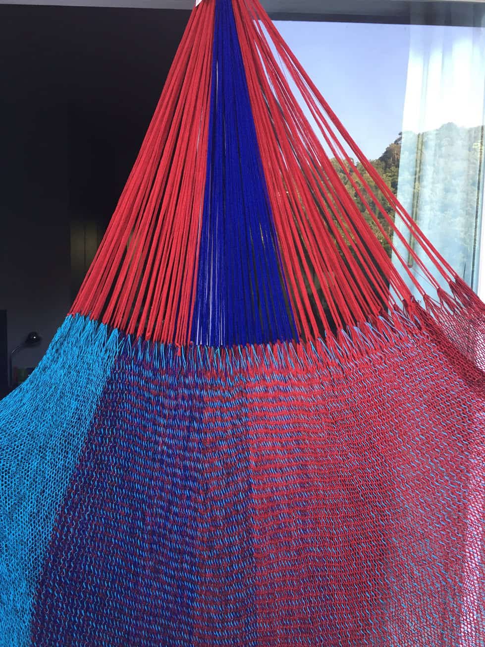 colse-up woven net hammock chair, "Monterosso" pattern, with bold sections of deep red, navy blue, and cool turquoise in a wide-stripe design.