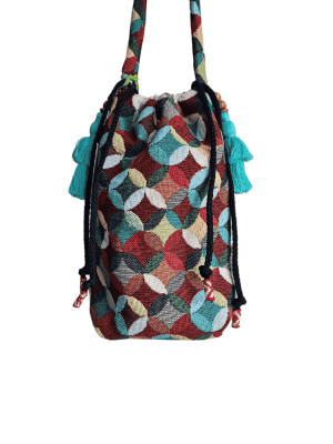 A stylish drawstring bucket bag or pouch bag featuring a vibrant, multi-color geometric fabric pattern with interlocking circle or Seigaiha wave motifs with bohemian style. The textile includes shades of teal, burgundy, olive green, cream, and brown. Decorated with tassels and wood beats