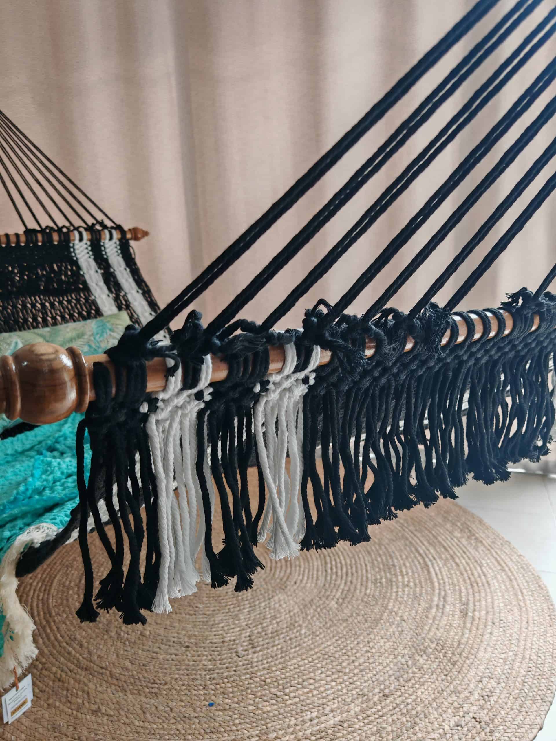 Close-up of the woven black and white rope hammock, wooden spreader bar.