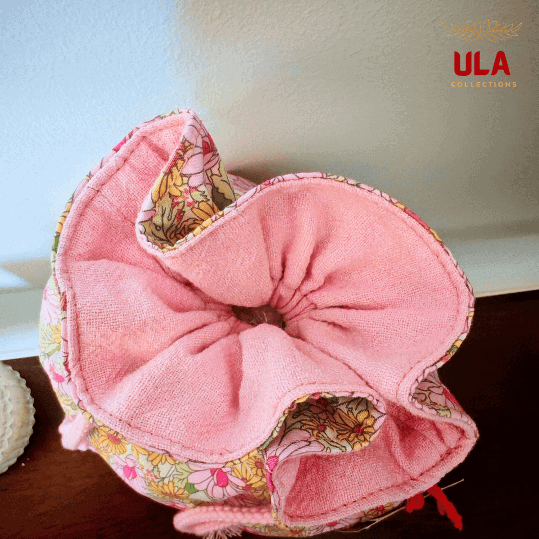 A top-down perspective looking into the open bag. The interior is lined with a soft, light pink fabric, and the gathered edges form a petal-like shape around the opening.