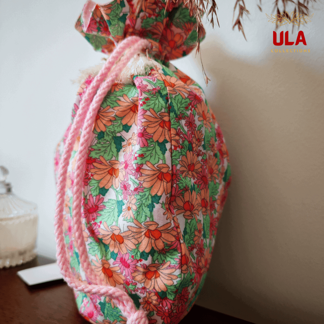 A side view of the bag featuring light pink braided drawstrings that complement the pink tones in the floral pattern.