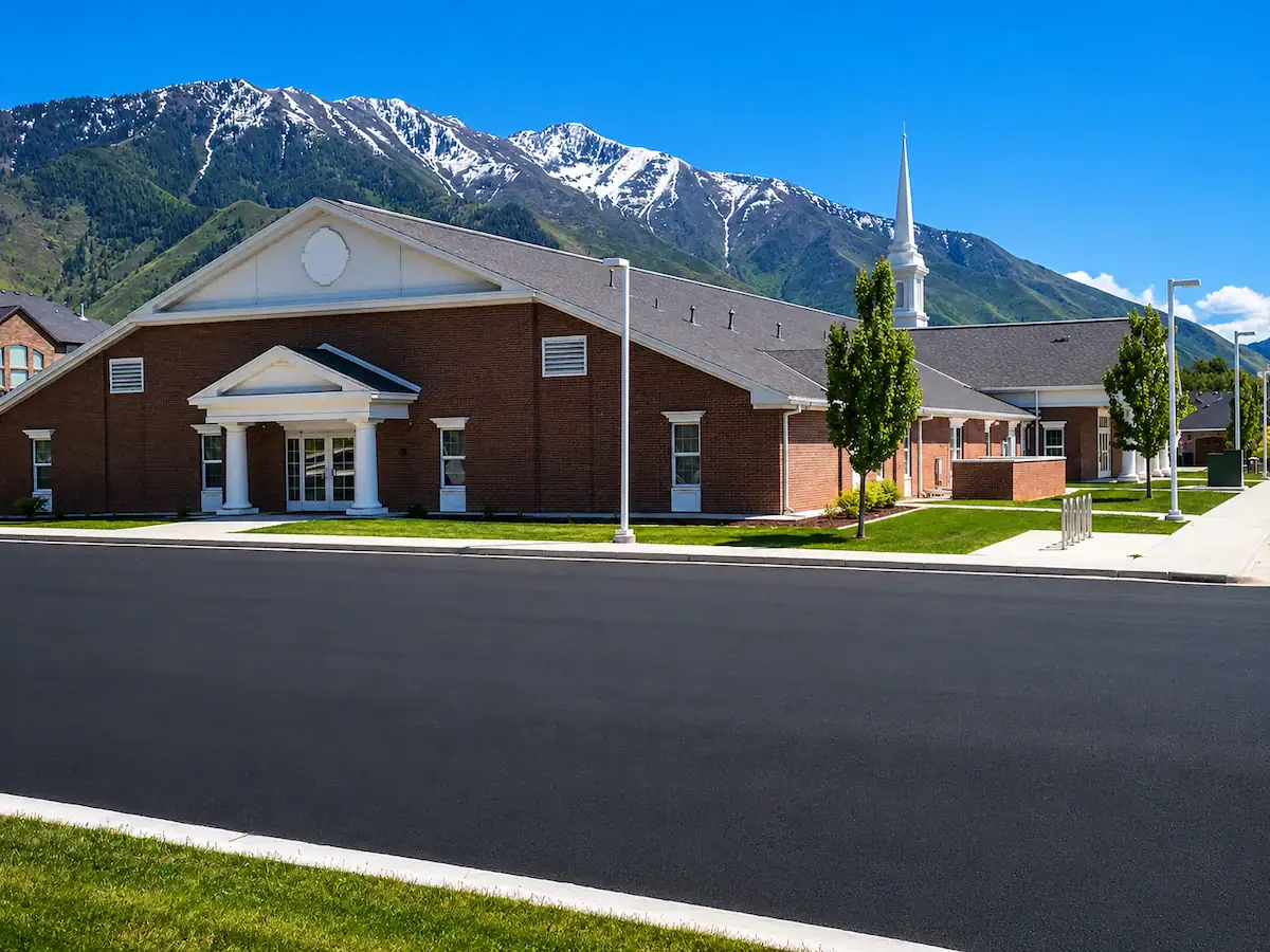 Freshly paved asphalt roadway in front of a church with Utah mountain backdrop