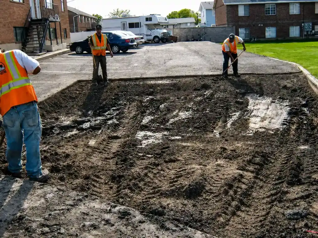 Full-depth asphalt patching excavation in a Utah parking lot with workers preparing the area for pavement repair.