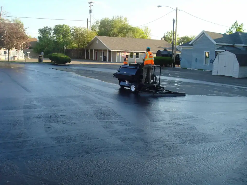 Worker applying asphalt sealcoating to a parking lot in Utah