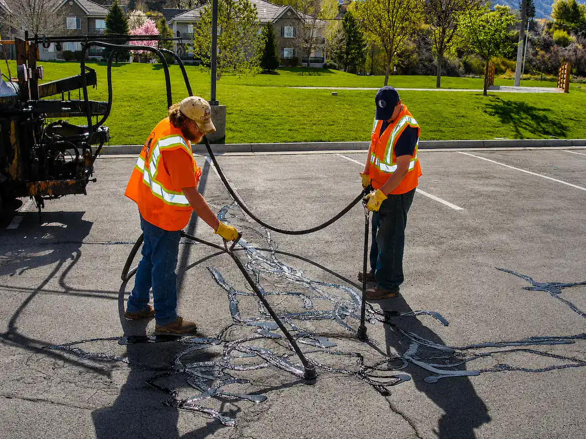 Asphalt crack sealing crew repairing pavement cracks in a Utah parking lot