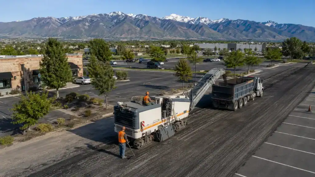 Aerial view of asphalt milling operations in a Utah commercial parking lot with construction crew and milling machine
