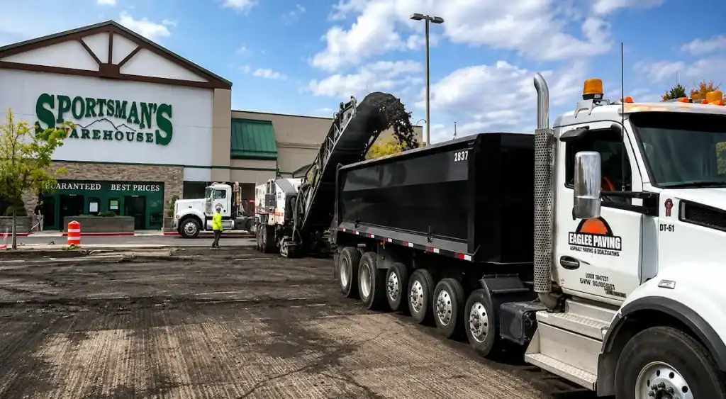 Asphalt milling machine loading reclaimed pavement into a dump truck during parking lot rehabilitation in Utah