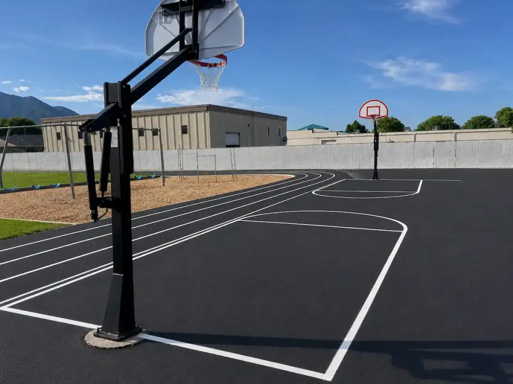 After photo of freshly sealcoated outdoor basketball court with bright new game markings at Timpanogos Academy in Lindon, Utah.